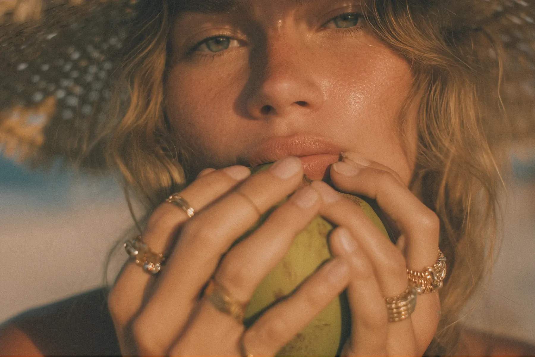 Woman in a straw hat holding a green coconut drink outdoors